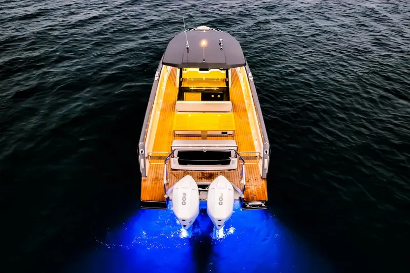 Slide: The Image of Schaefer V33 2025 boat with illuminated deck and twin outboard motors on water. - 38