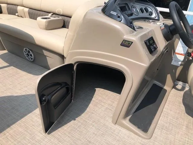 Slide: The Image of 2023 Sun Tracker Party Barge 22 DLX interior with open storage compartment and beige seating. - 14