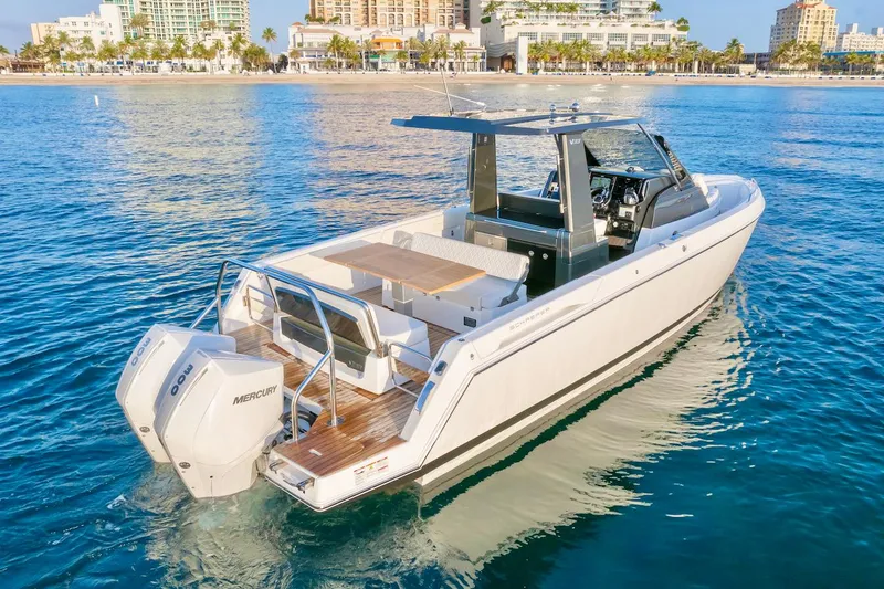 Slide: The Image of 2025 Schaefer V33 boat with twin Mercury engines on calm water near a beach. - 4