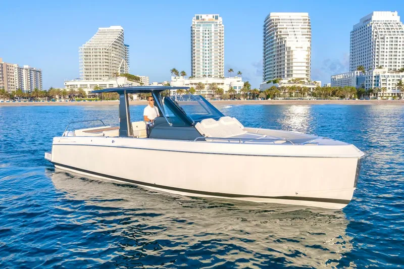 Slide: The Image of 2025 Schaefer V33 boat cruising near a coastal city skyline. - 8