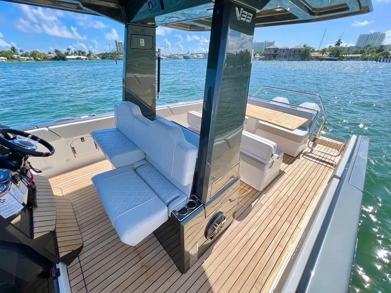 Slide: The Image of 2025 Schaefer V33 boat interior with white seating and wooden deck on a sunny day. - 14