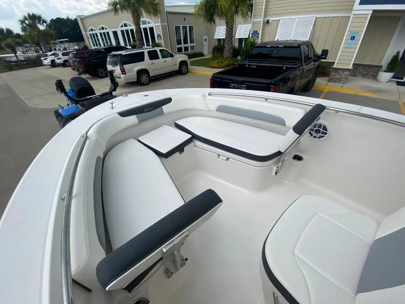 Slide: The Image of 2024 Robalo 202 EXPLORER boat interior with white and black seating, docked at a marina. - 16