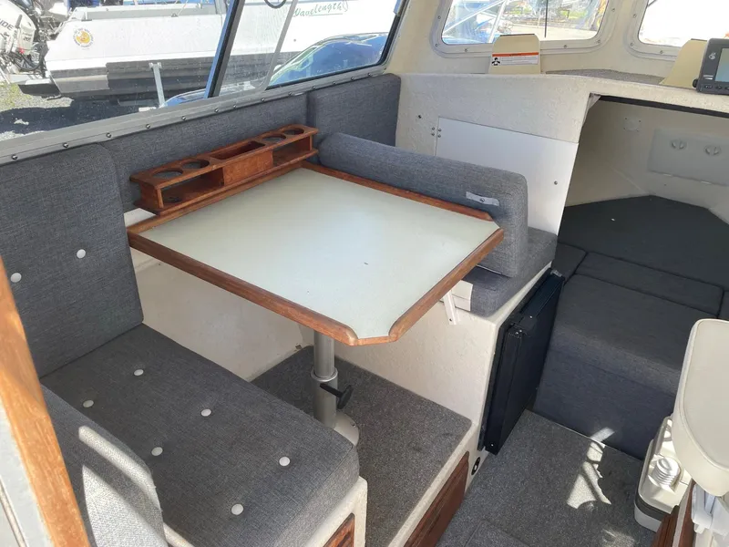 Slide: The Image of 2004 SeaSport 2400 XL interior dining area with table and cushioned seating. - 13