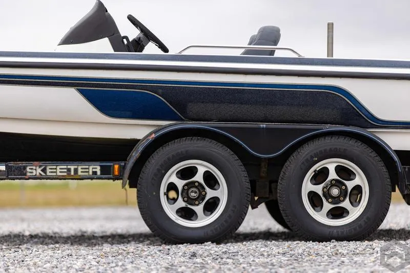 Slide: The Image of 2004 Skeeter ZX225 boat on a dual-axle trailer with white and blue detailing. - 13