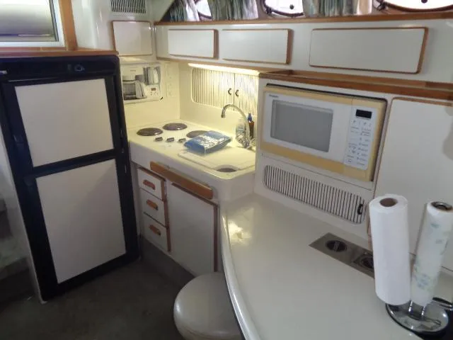 Slide: The Image of 1995 Sea Ray 400 Express Cruiser kitchen with microwave, stove, and refrigerator. - 13