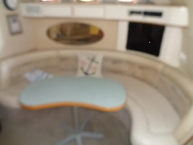 Slide: The Image of Interior seating area of a 1995 Sea Ray 400 Express Cruiser with a curved sofa and table. - 6