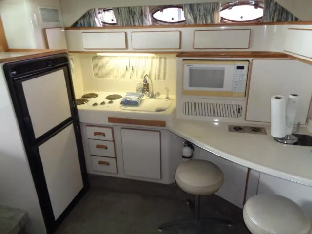 Slide: The Image of 1995 Sea Ray 400 Express Cruiser kitchen with microwave, stove, and seating area. - 7
