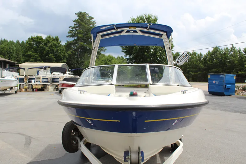 Slide: The Image of 2007 Bayliner 185 Bowrider boat on trailer, parked outdoors with trees in background. - 3