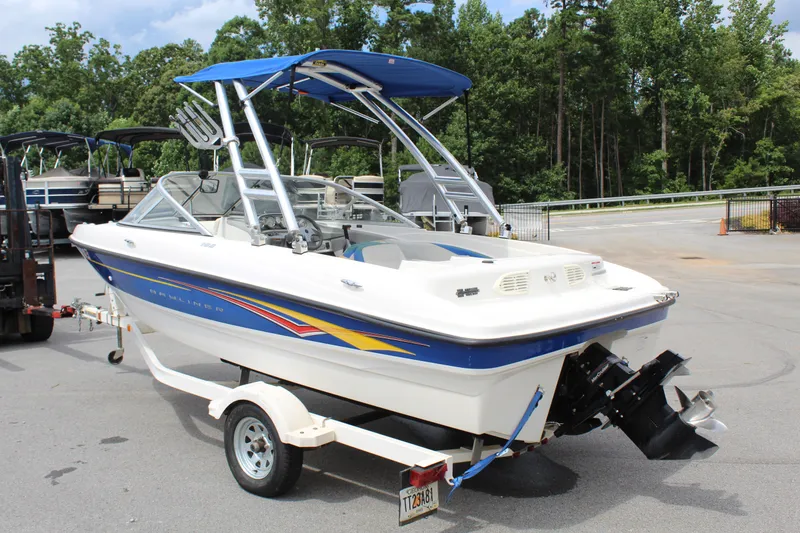 Slide: The Image of 2007 Bayliner 185 Bowrider boat on trailer, parked outdoors with trees in background. - 7