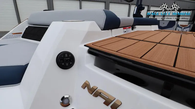 Slide: The Image of 2024 Nautique GS24 boat rear deck with teak flooring and JL Audio controls. - 13