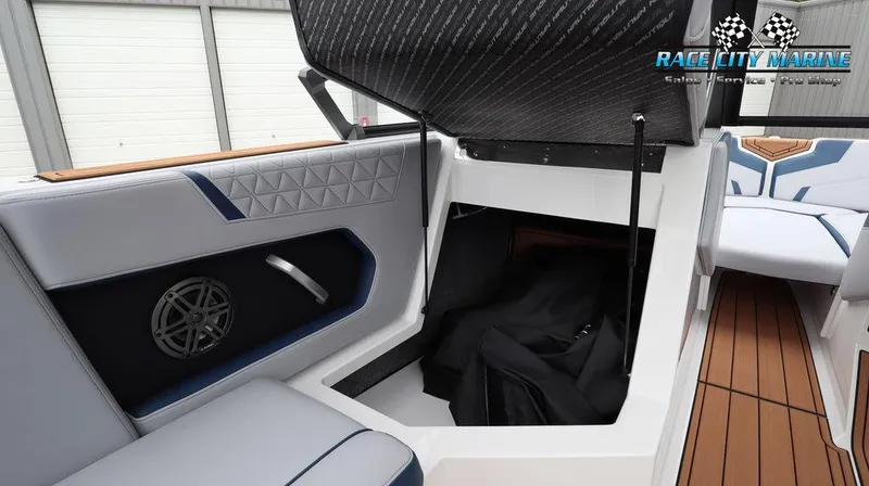 Slide: The Image of 2024 Nautique GS24 boat interior storage compartment with cushioned seating and speaker. - 30