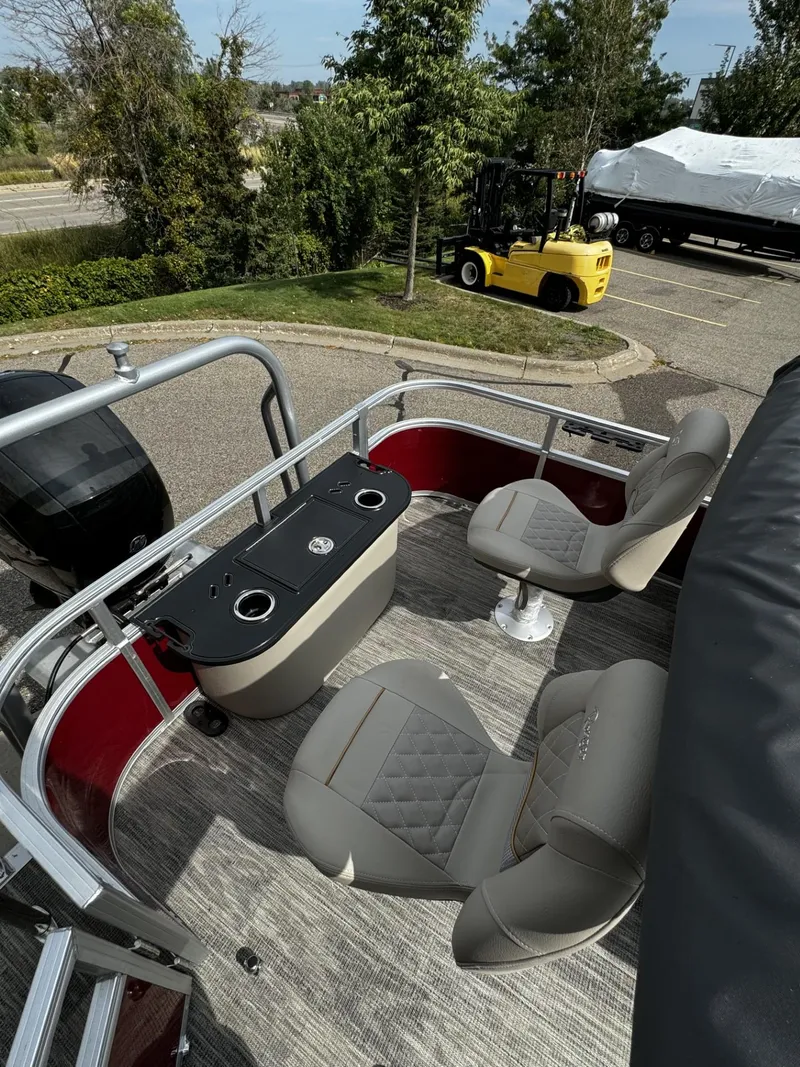 Slide: The Image of 2024 Ranger Reata 220F pontoon boat with seating and table, parked outdoors. - 6