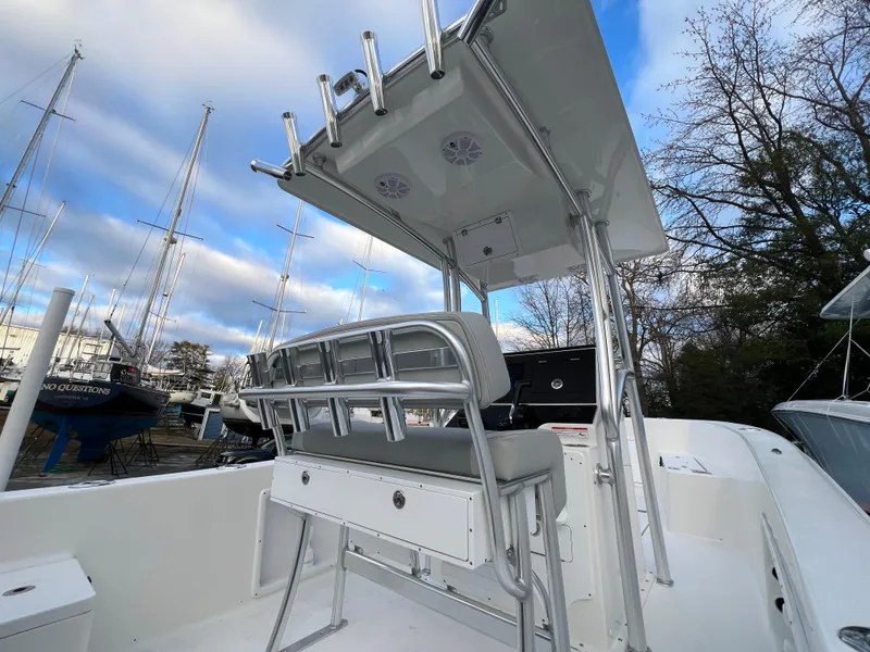 Slide: The Image of 2024 KenCraft 21 boat with T-top and seating, docked near sailboats. - 9