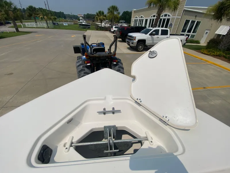 Slide: The Image of 2024 Key West 203 FS boat anchor compartment with open lid, parked near trucks and buildings. - 22