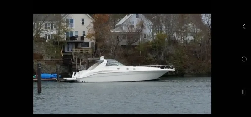 Slide: The Image of 1995 Sea Ray 450 Sundancer yacht docked near waterfront homes. - 4