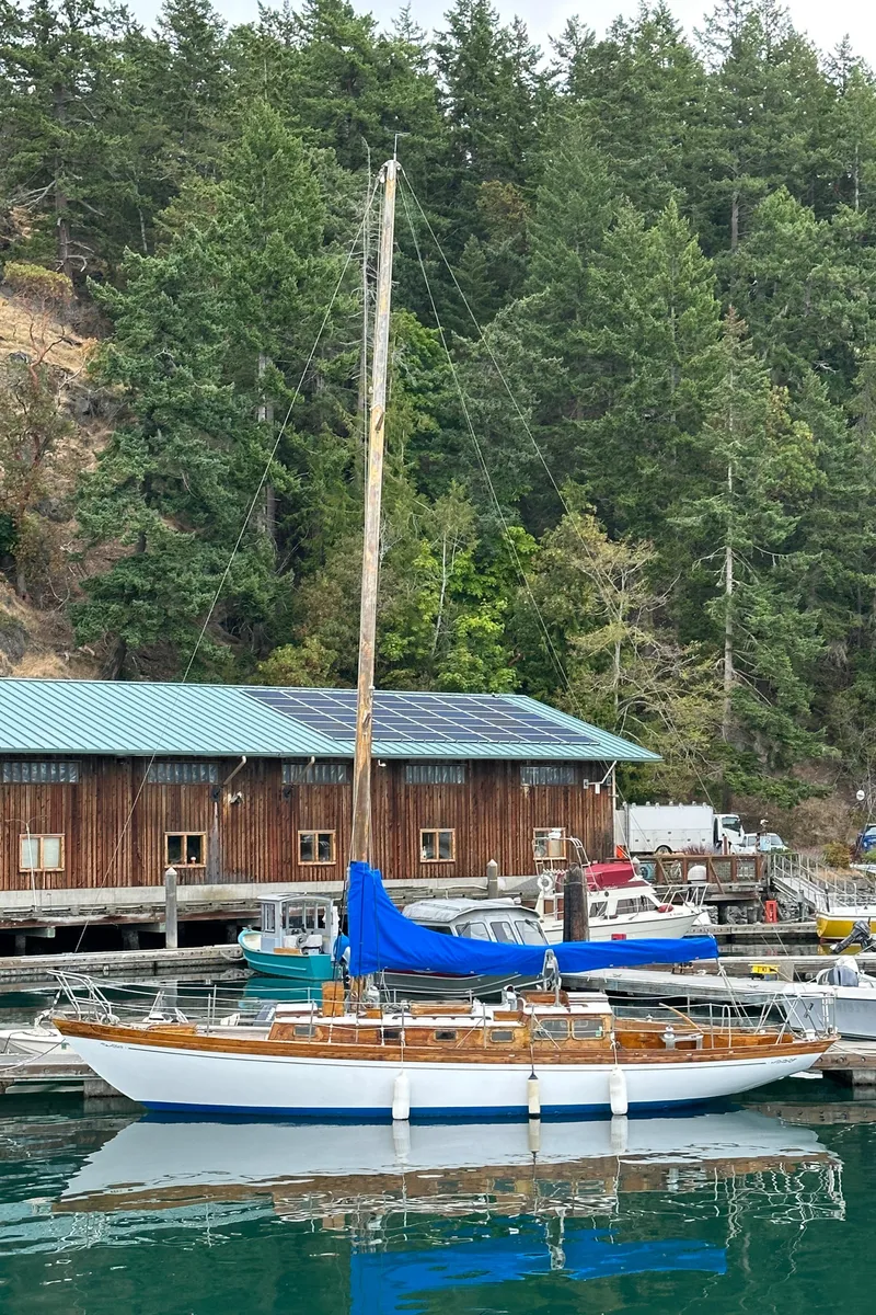 Slide: The Image of 1964 Cheoy Lee Lion Class Sloop docked at a marina with forest backdrop. - 2