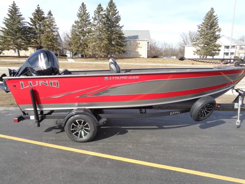 The Image of 2023 Lund 1775 Pro Guide fishing boat on trailer, red and gray. - 0
