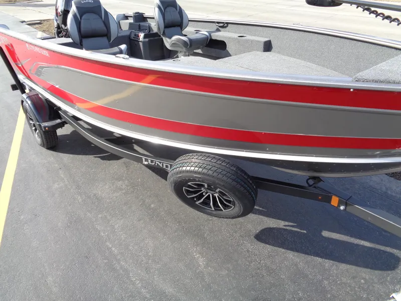 Slide: The Image of 2023 Lund 1775 Pro Guide fishing boat on trailer, red and gray exterior. - 2