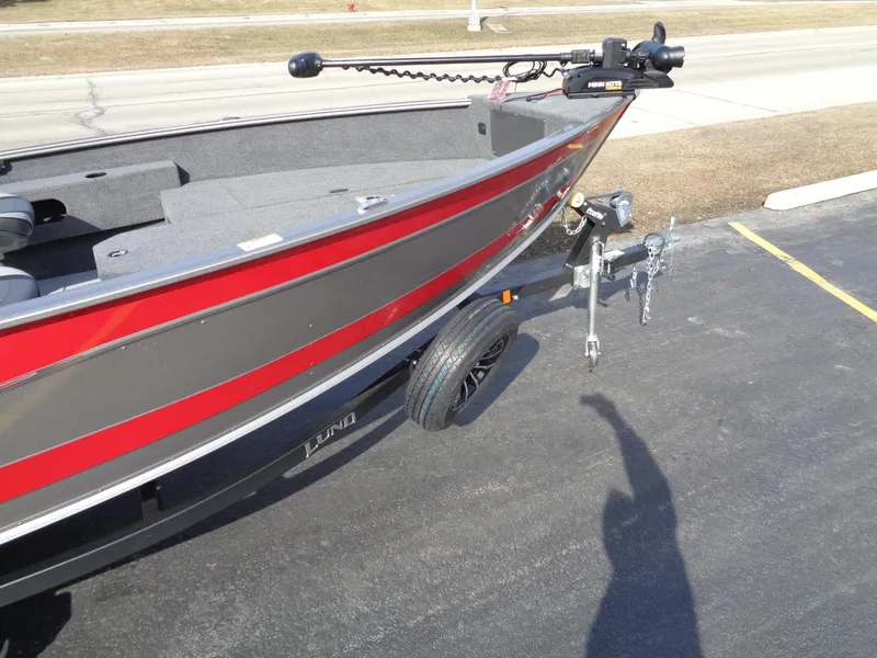 Slide: The Image of 2023 Lund 1775 Pro Guide boat on trailer, red and gray, parked on asphalt. - 4