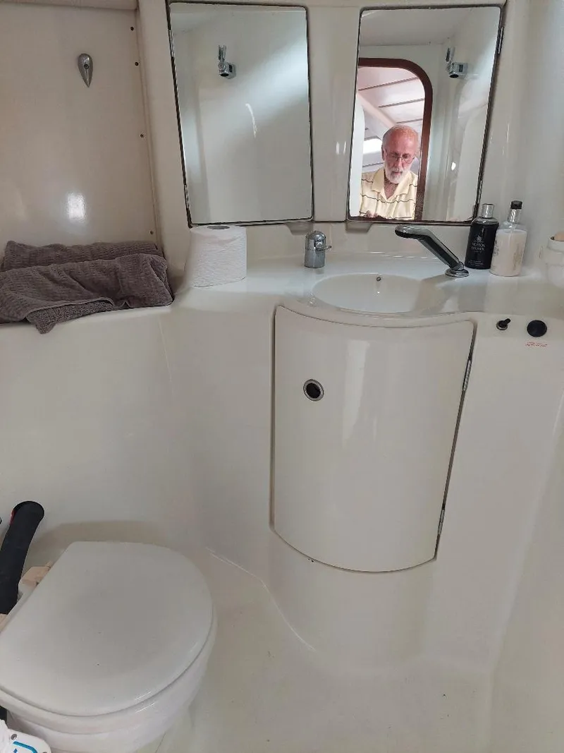 Slide: The Image of Beneteau Oceanis 351 bathroom interior, featuring sink, mirror, and toilet, 1995 model. - 37