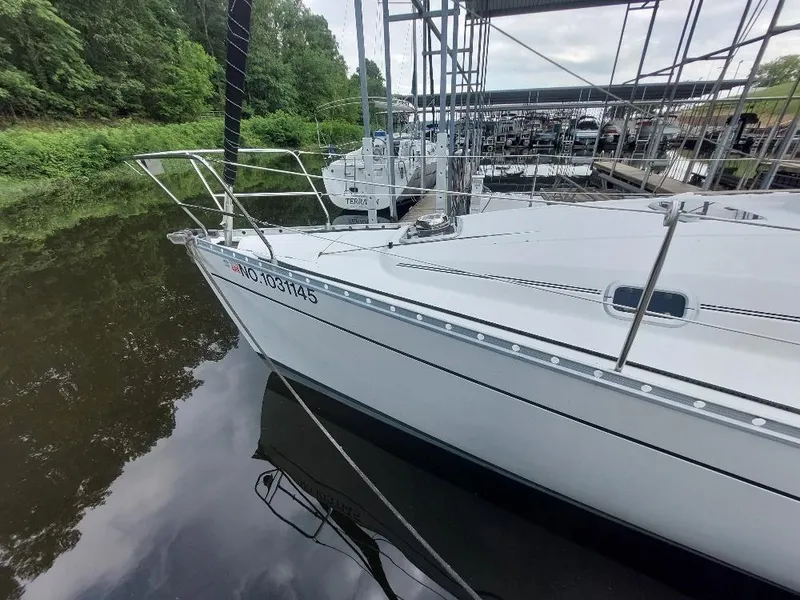 Slide: The Image of 1995 Beneteau Oceanis 351 sailboat docked in a marina, surrounded by lush greenery. - 6