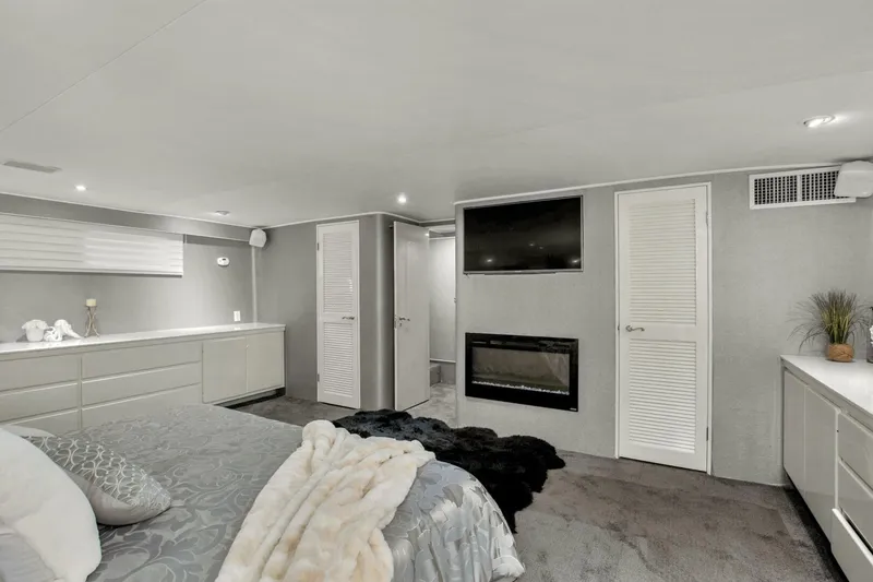 Slide: The Image of Luxurious bedroom interior of 1983 Broward 108 Cockpit Motor Yacht with modern decor and fireplace. - 11