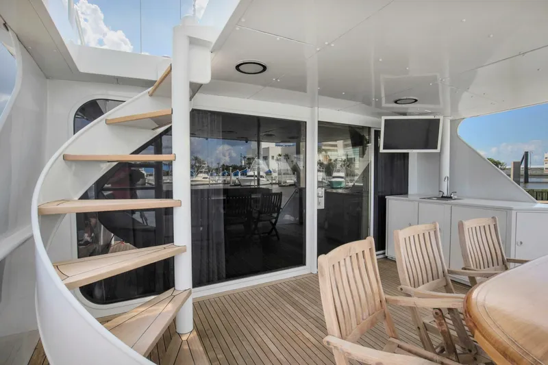 Slide: The Image of 1983 Broward 108 Cockpit Motor Yacht, outdoor seating area with spiral staircase and TV. - 36