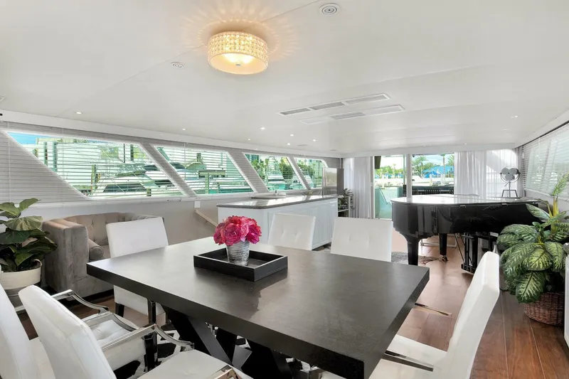 Slide: The Image of Luxurious interior of 1983 Broward 108 Cockpit Motor Yacht with modern dining area and grand piano. - 6