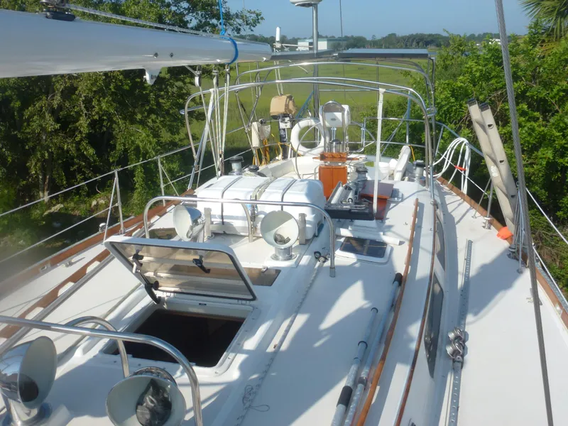 Slide: The Image of 1990 Sabre 425 sailboat deck with open hatches and lush green surroundings. - 14