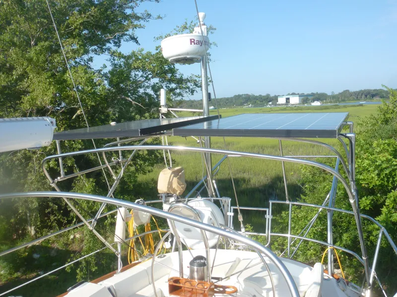 Slide: The Image of Sabre 425 sailboat (1990) with solar panels and radar, docked in a lush green area. - 16
