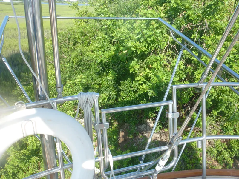 Slide: The Image of Sabre 425 sailboat deck with stainless steel railings, life ring, and lush green background, 1990 model. - 20