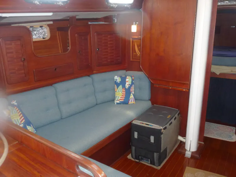 Slide: The Image of Interior of a 1990 Sabre 425 sailboat with blue cushioned seating and wooden cabinetry. - 33