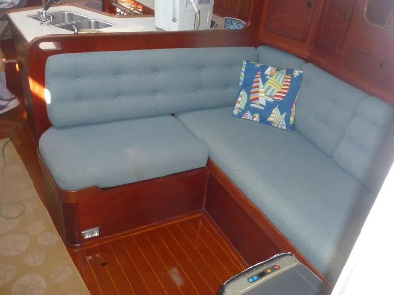Slide: The Image of 1990 Sabre 425 yacht interior with blue cushioned seating and wooden flooring. - 40
