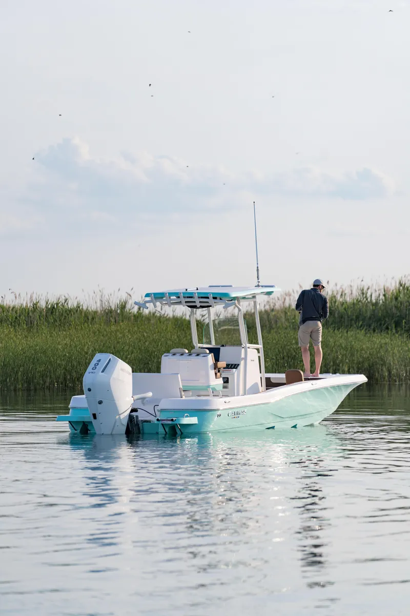 Slide: The Image of 2024 Caymas 28 Hybrid boat on calm water with a person standing on deck. - 8