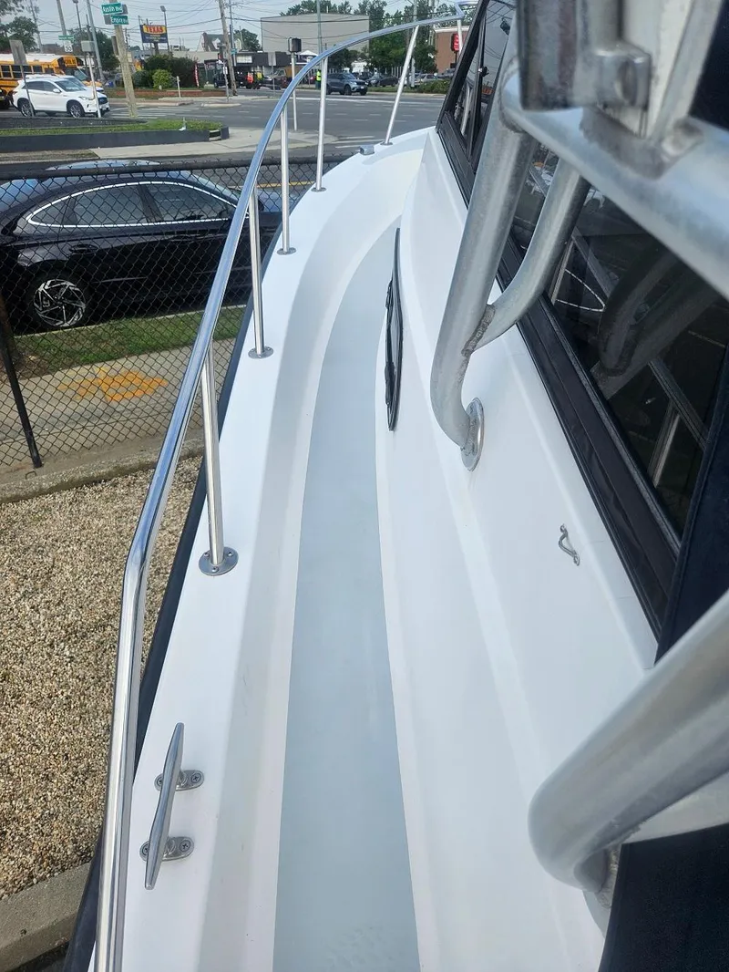 Slide: The Image of 1992 Boston Whaler 23 Walkaround boat deck with railing, parked near a road. - 7