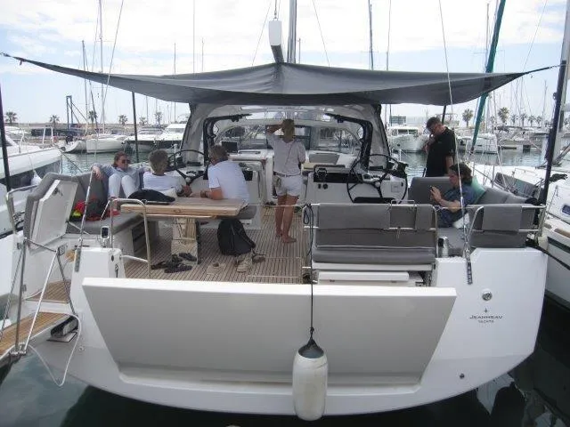 Slide: The Image of 2024 Jeanneau 55 yacht with people relaxing on deck at a marina. - 7