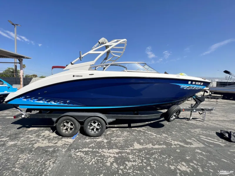 Slide: The Image of 2021 Yamaha AR250 boat on trailer, blue and white design, parked outdoors. - 0