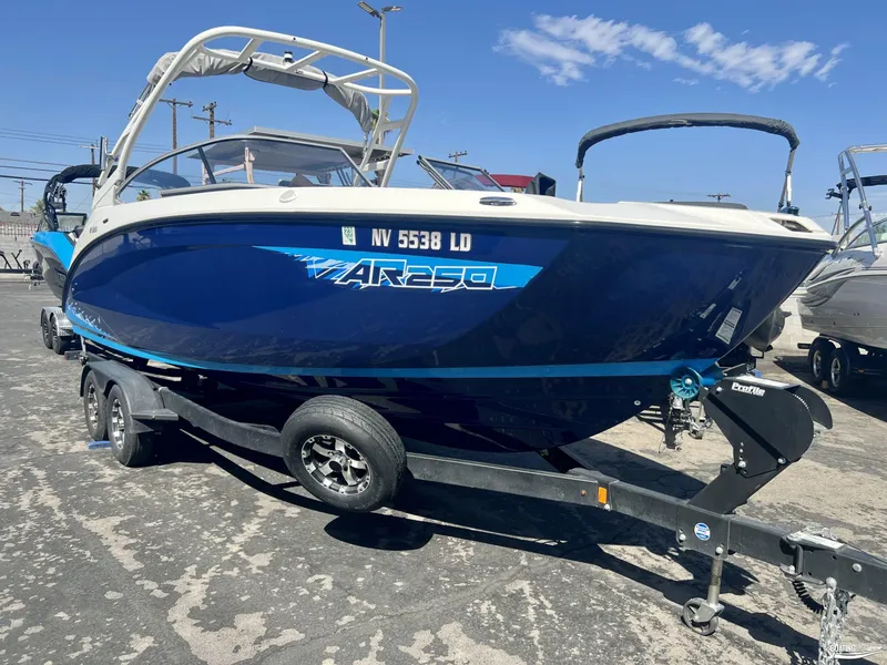 Slide: The Image of 2021 Yamaha AR250 boat on trailer, blue and white design, parked outdoors. - 1