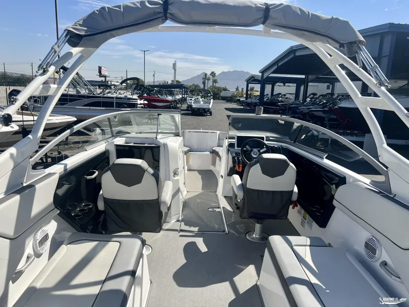 Slide: The Image of 2021 Yamaha Boats AR250 interior with seating and steering wheel, docked outdoors. - 2