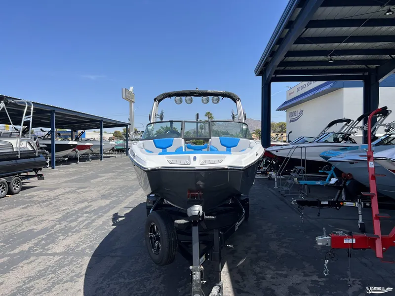 Slide: The Image of 2023 MasterCraft XT22 boat on trailer at dealership under clear blue sky. - 2