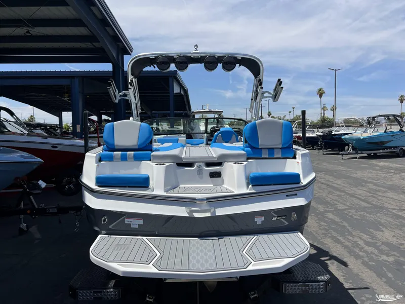 Slide: The Image of 2023 MasterCraft XT22 boat with blue and white seating, docked outdoors. - 3