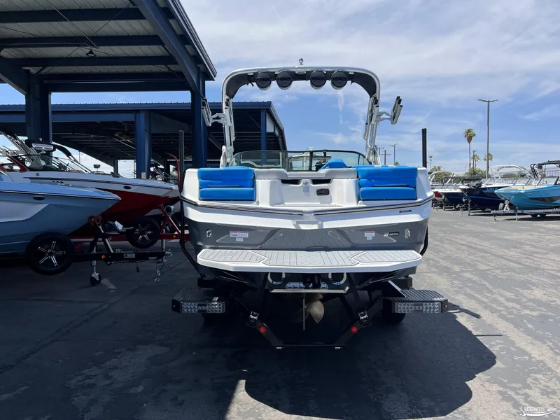 Slide: The Image of 2023 MasterCraft XT22 boat with blue seating, parked in a marina. - 4