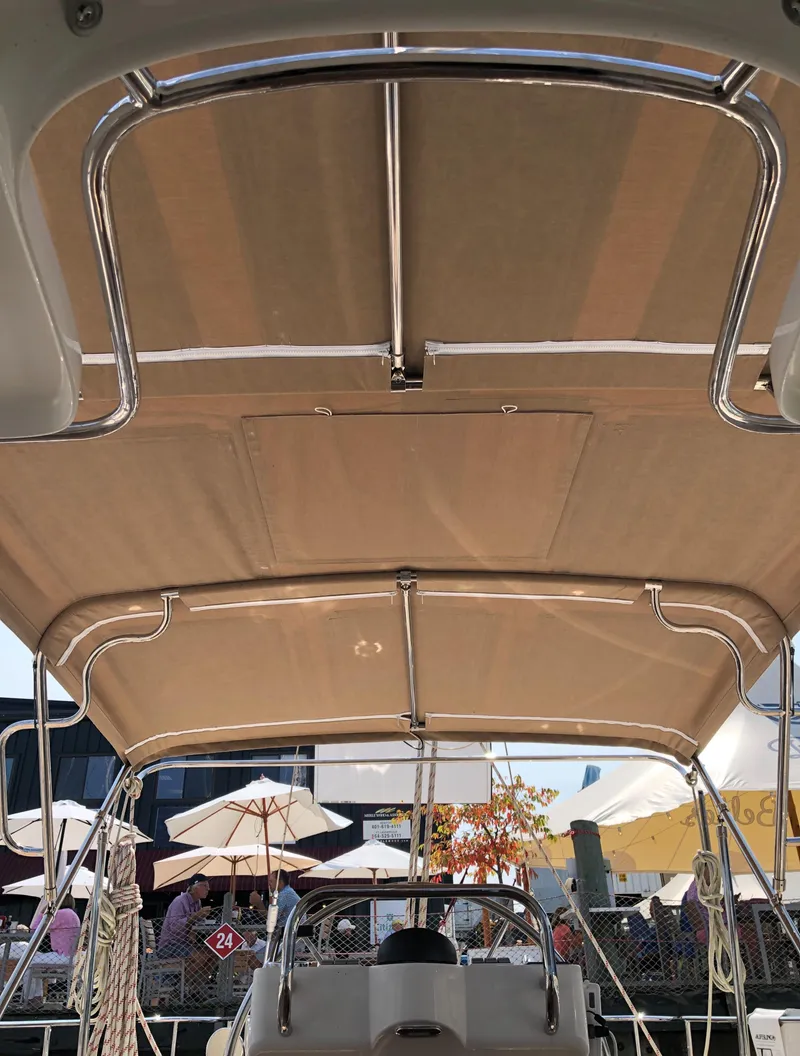 Slide: The Image of Outbound 56 sailboat cockpit with beige canopy, 2020 model, docked near umbrellas and people. - 40