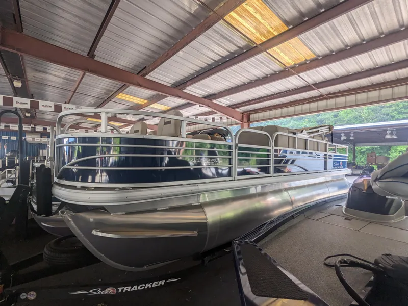 The Image of 2024 Sun Tracker Fishin' Barge 22 XP3 pontoon boat in covered storage. - 0