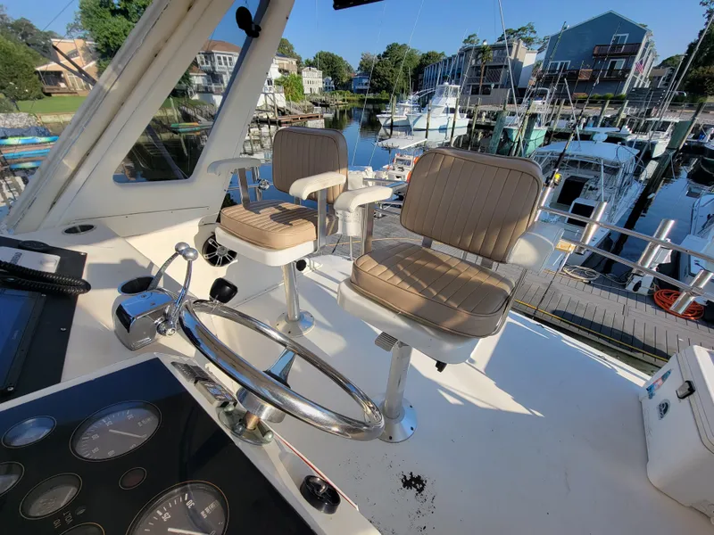 Slide: The Image of Cockpit view of 1991 Ocean Yachts 42 Super Sport with helm chairs and marina background. - 19