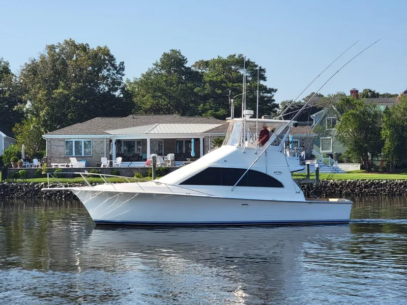 Slide: The Image of 1991 Ocean Yachts 42 Super Sport cruising on a calm river near waterfront homes. - 5