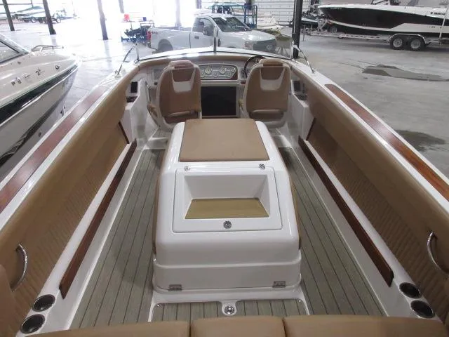 Slide: The Image of 2023 Thoroughbred u23i boat interior with tan seating and wooden accents in a showroom. - 12