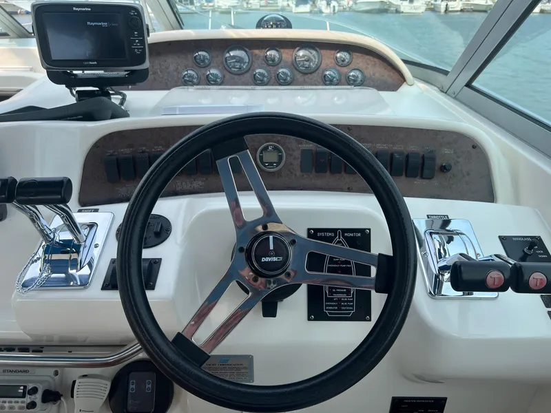 Slide: The Image of 1996 Sea Ray 330 Sundancer helm with steering wheel and navigation controls. - 28