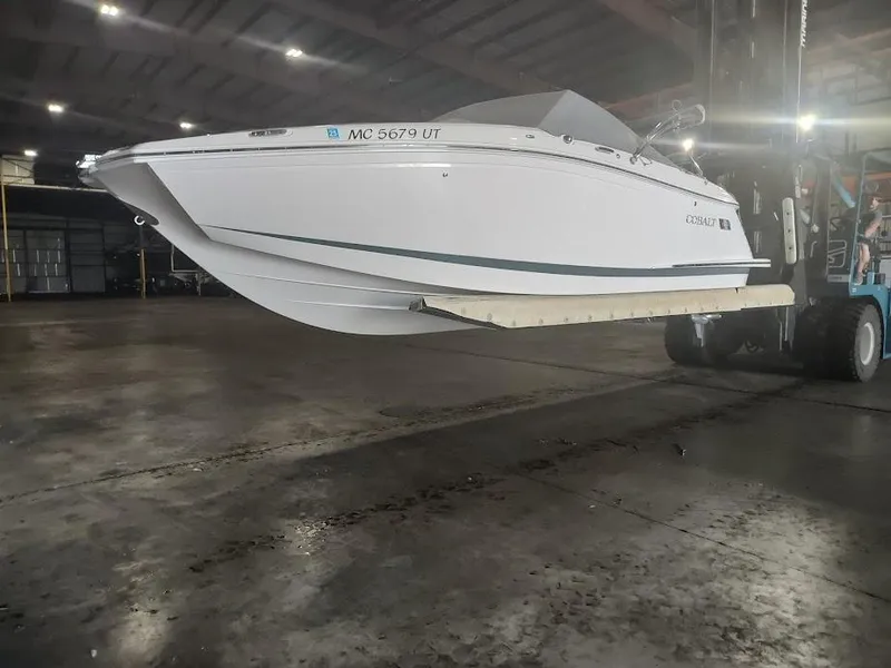 The Image of 2022 Cobalt 23SC boat in a warehouse, lifted by a forklift. - 0