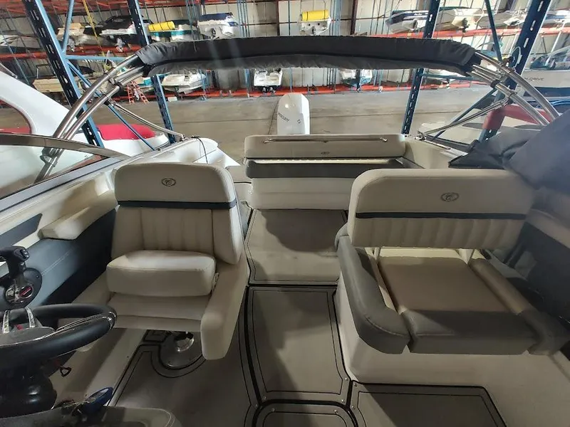 Slide: The Image of 2022 Cobalt 23SC boat interior with seating and steering wheel in a warehouse. - 23